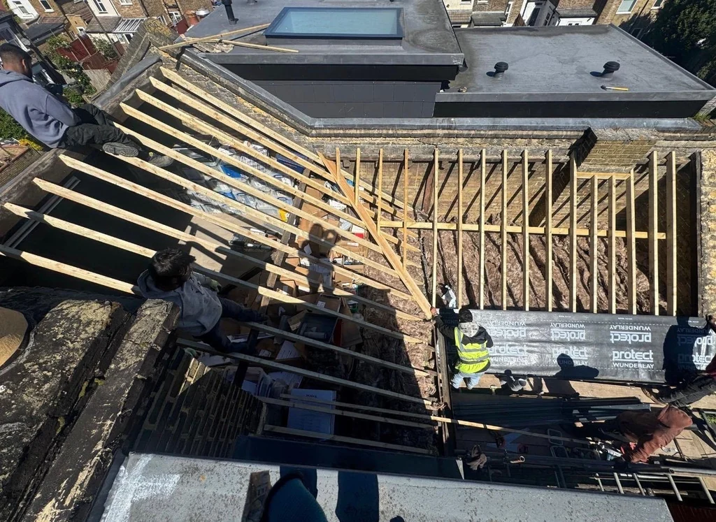 Workers beside exposed timber rafters and a flat roof with rooflight