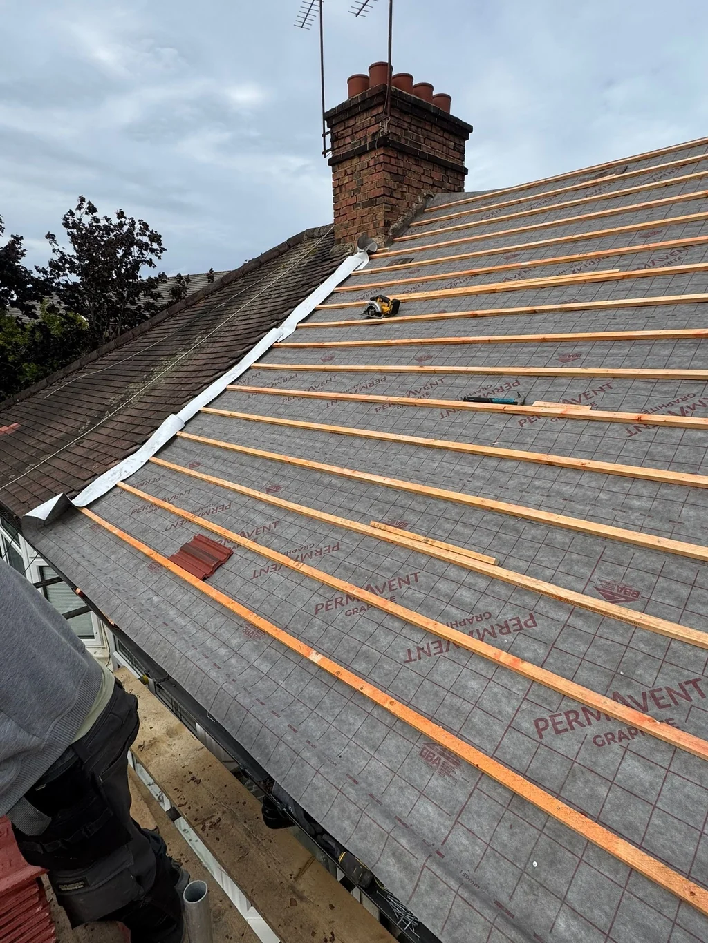 Roof membrane and battens beside a brick chimney