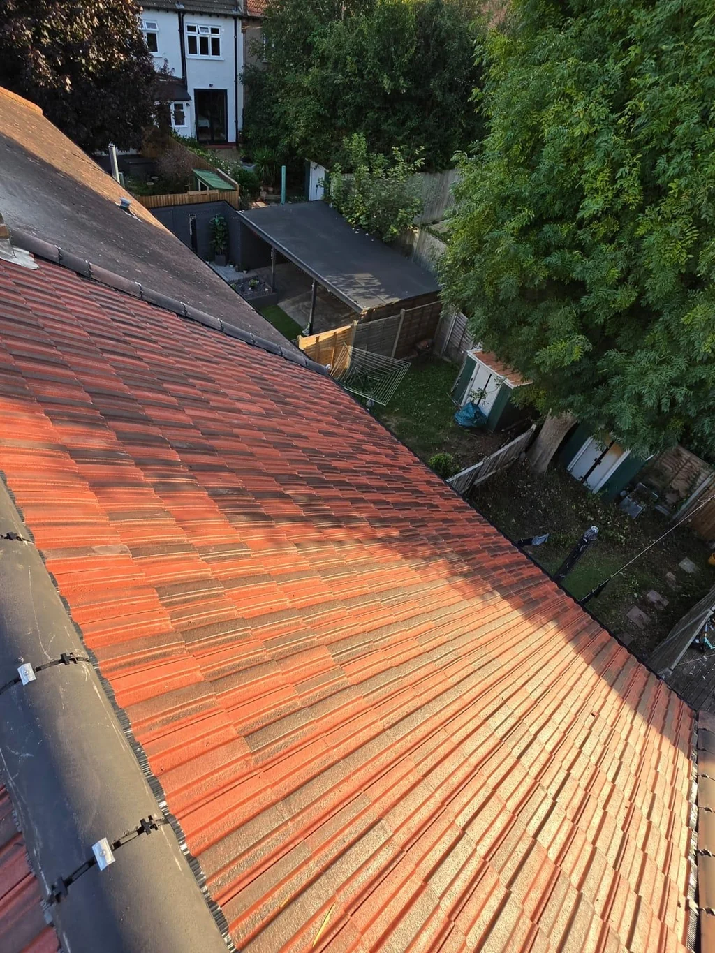 Red tiled roof slope beside a dark ridge above rear gardens
