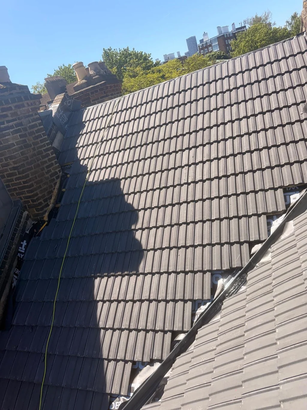 Grey interlocking roof tiles beside a brick party wall