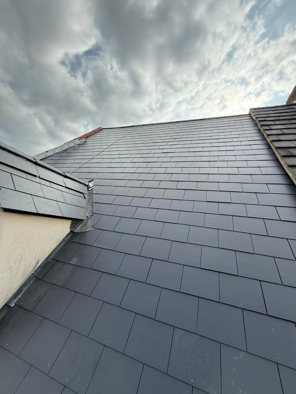Grey slate-style roof courses beside a dormer cheek