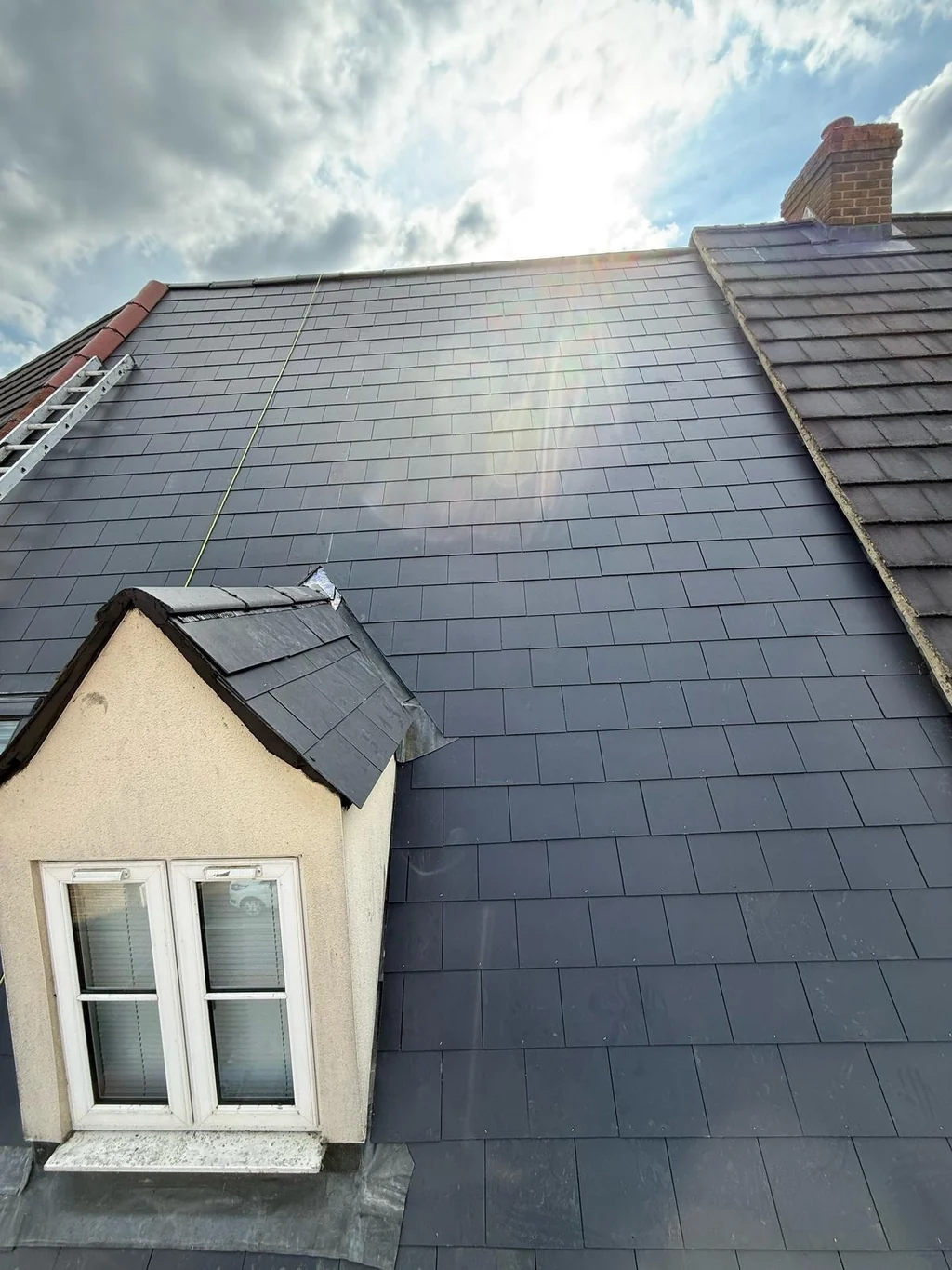 Grey slate-style roof courses around a white dormer window